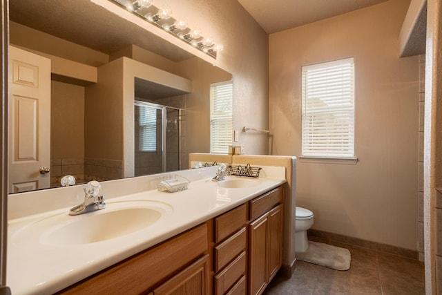 bathroom featuring toilet, vanity, tile patterned floors, and a shower with door