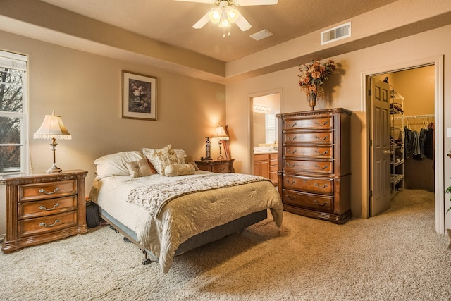 carpeted bedroom featuring ceiling fan, ensuite bath, a spacious closet, and a closet