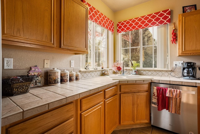 kitchen featuring tile patterned floors, tile countertops, stainless steel dishwasher, and sink