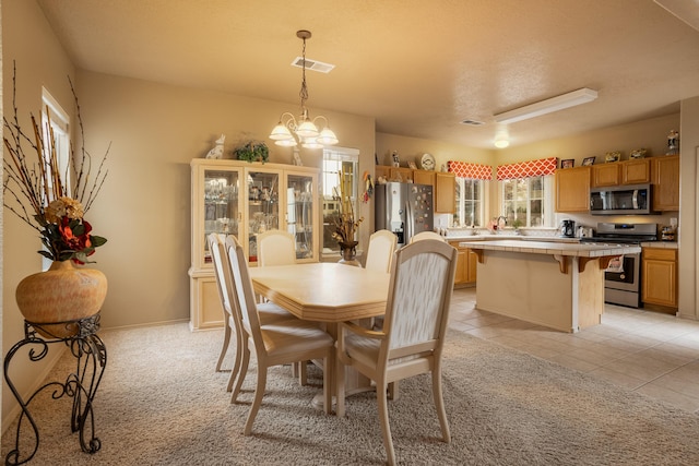 dining space featuring sink, light tile patterned floors, and an inviting chandelier