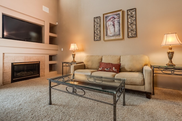 carpeted living room featuring built in shelves and a tiled fireplace