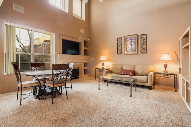 carpeted living room featuring a towering ceiling