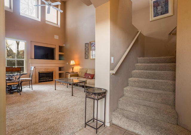 interior space with carpet flooring, built in shelves, ceiling fan, a high ceiling, and a fireplace