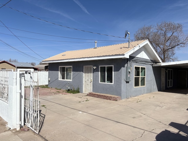 view of front of house featuring a gate, stucco siding, metal roof, and fence