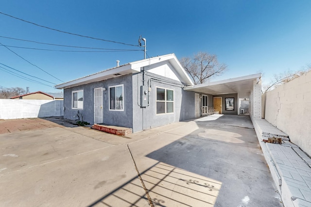 view of front of property featuring driveway, a patio area, a fenced backyard, and stucco siding