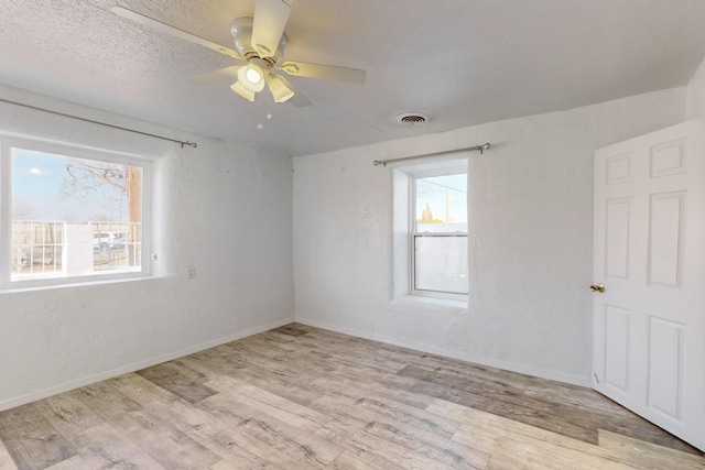 empty room with ceiling fan, light hardwood / wood-style flooring, and a textured ceiling