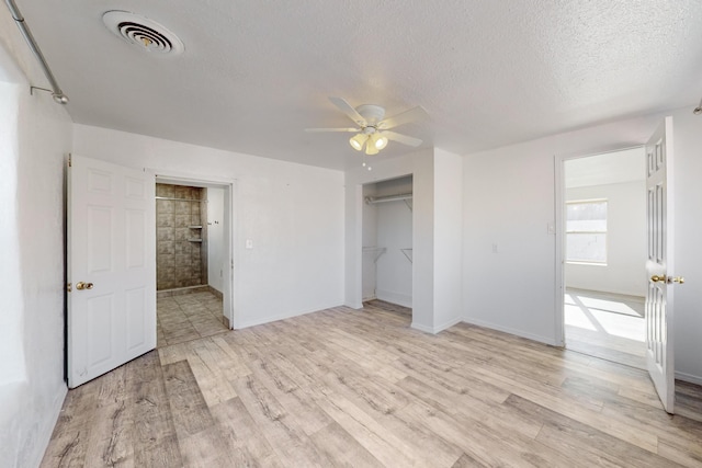 unfurnished bedroom with a closet, a textured ceiling, ceiling fan, and light hardwood / wood-style floors