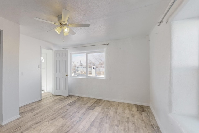 empty room with a textured ceiling, ceiling fan, and light hardwood / wood-style floors