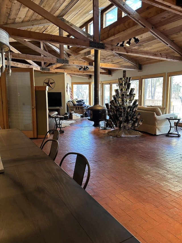 dining room featuring a healthy amount of sunlight, vaulted ceiling with beams, and wood ceiling