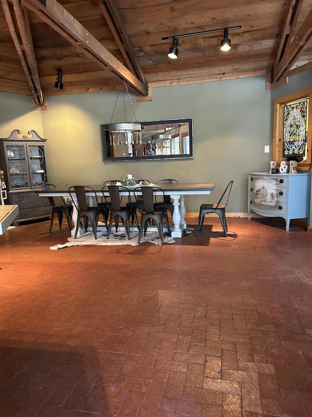 dining room featuring rail lighting, wooden ceiling, and vaulted ceiling with beams