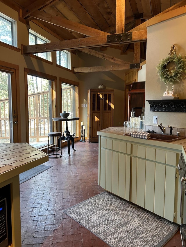 kitchen with sink, tile countertops, and lofted ceiling with beams