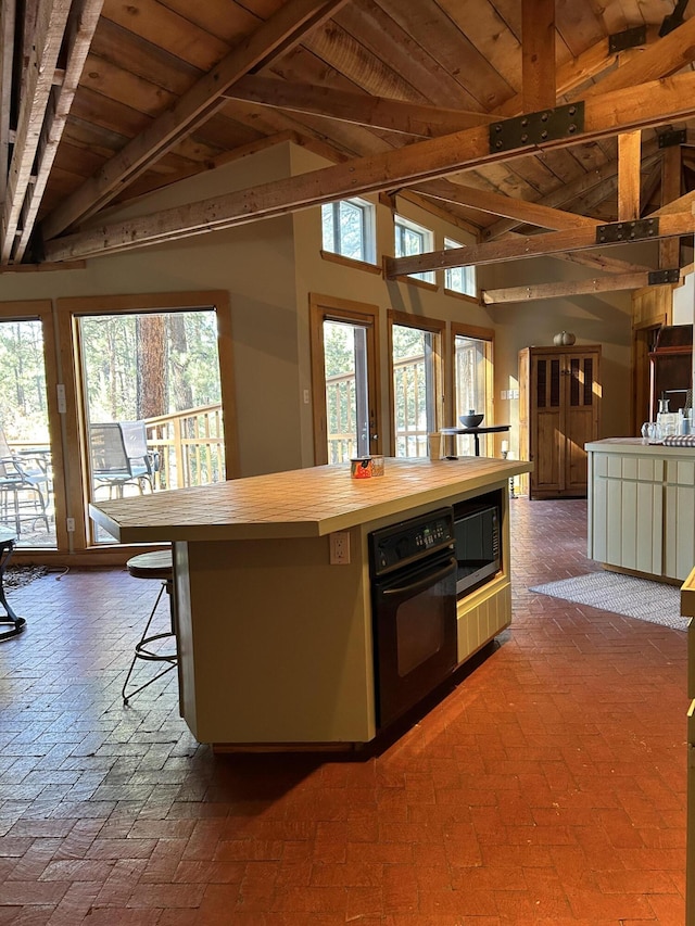 kitchen featuring black oven, wood ceiling, butcher block countertops, lofted ceiling with beams, and built in microwave