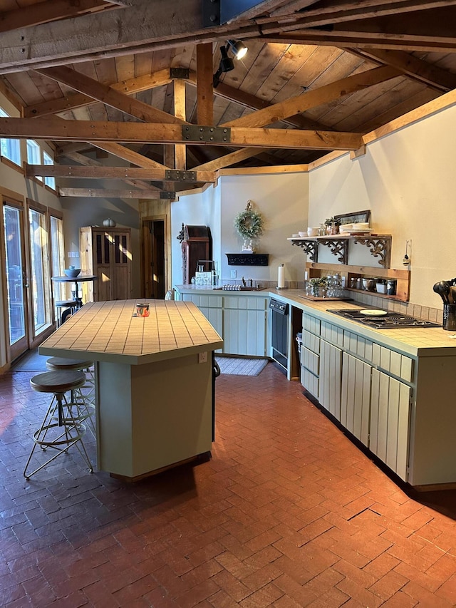 kitchen with wooden ceiling, tile countertops, a kitchen bar, kitchen peninsula, and beam ceiling