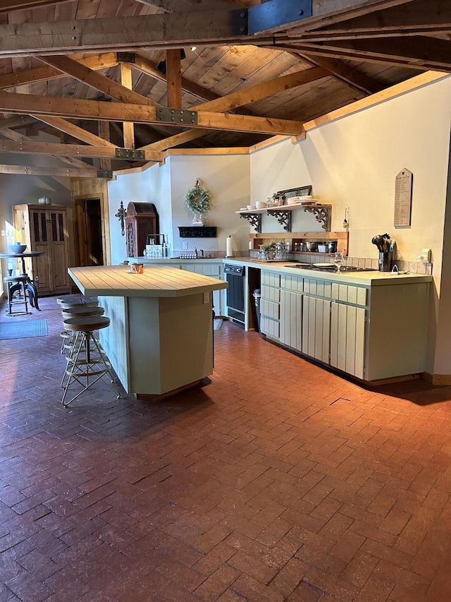 kitchen with a kitchen bar, lofted ceiling with beams, tile countertops, and wood ceiling