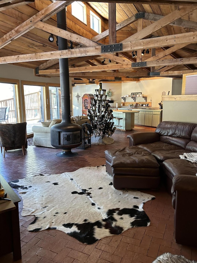 living room with high vaulted ceiling, wooden ceiling, a wood stove, and beam ceiling