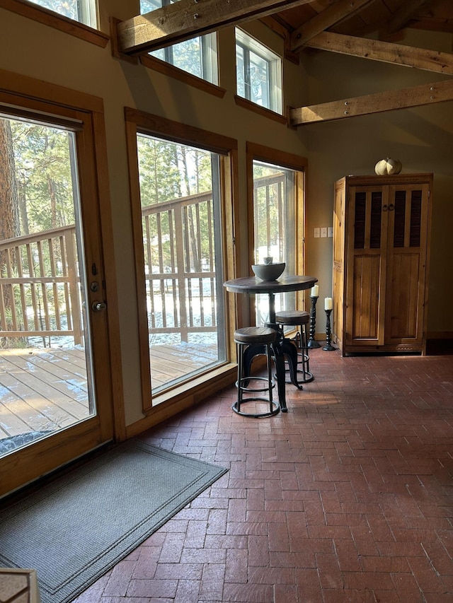 doorway featuring a towering ceiling, beamed ceiling, and plenty of natural light