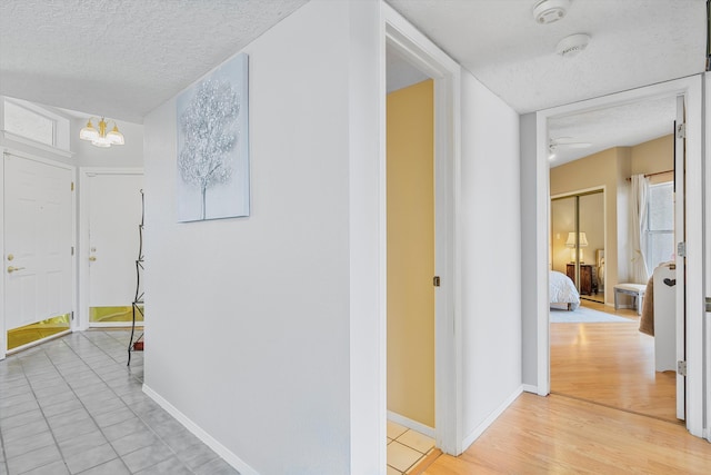 hallway featuring light hardwood / wood-style flooring and a textured ceiling