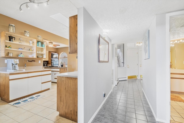 hallway featuring light tile patterned flooring, a baseboard heating unit, and a textured ceiling