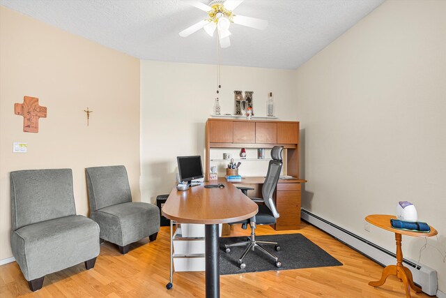 office area with baseboard heating, ceiling fan, light hardwood / wood-style floors, and a textured ceiling