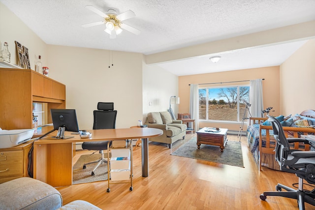 home office with ceiling fan, lofted ceiling, light hardwood / wood-style floors, and a textured ceiling