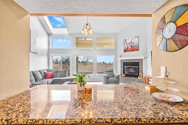 living room with high vaulted ceiling, a textured ceiling, a tile fireplace, and a chandelier