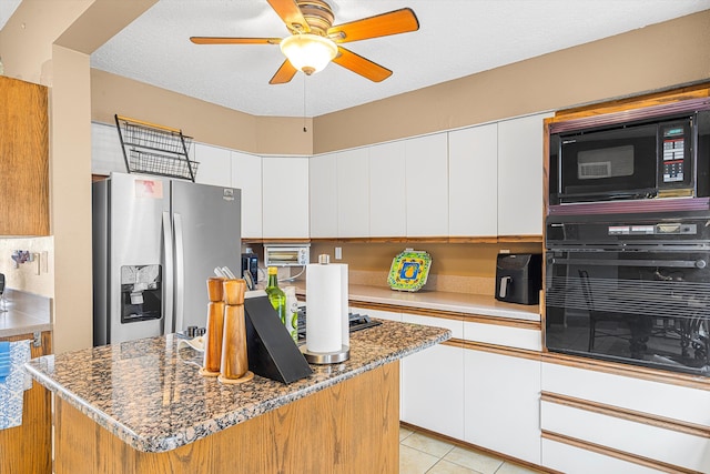 kitchen featuring dark stone countertops, white cabinets, light tile patterned floors, ceiling fan, and black appliances