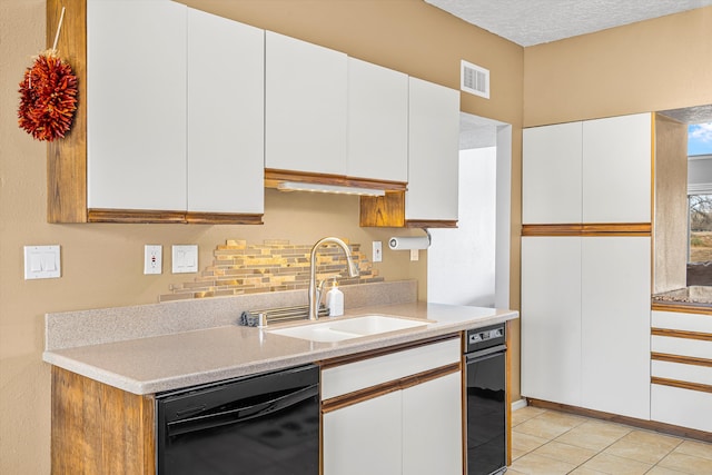 kitchen with light tile patterned floors, sink, dishwasher, a textured ceiling, and white cabinets