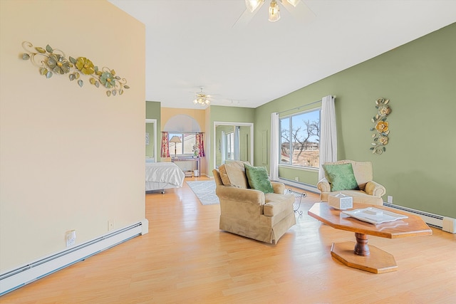 living area with ceiling fan, light hardwood / wood-style floors, and a baseboard heating unit