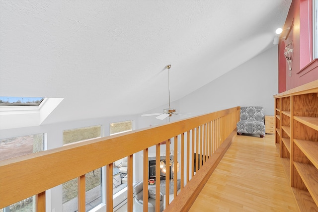 hallway featuring hardwood / wood-style floors, a textured ceiling, and vaulted ceiling with skylight