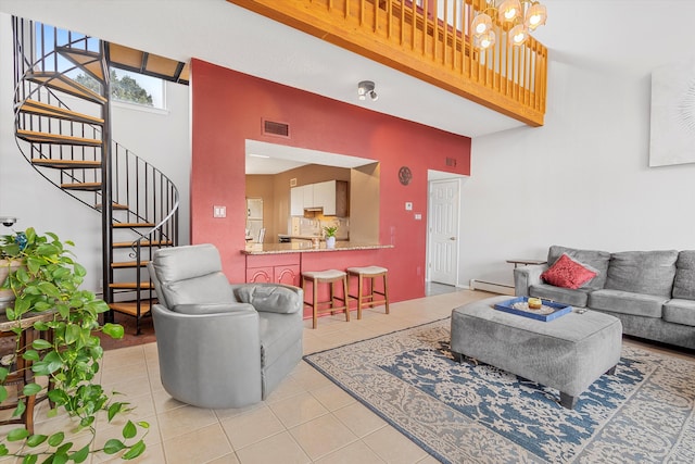 tiled living room with a chandelier, a high ceiling, and a baseboard heating unit