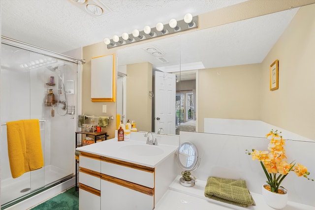 bathroom with vanity, a shower with door, and a textured ceiling