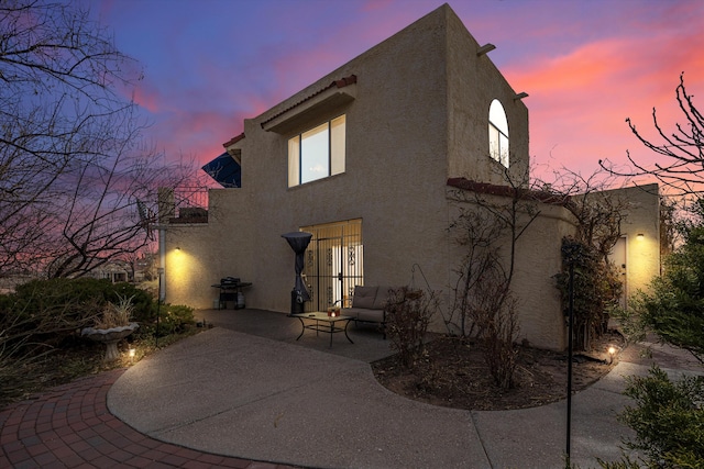 back house at dusk featuring a patio area