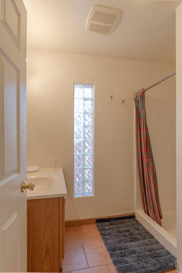 bathroom with tile patterned flooring, vanity, and walk in shower