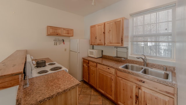 kitchen with light tile patterned floors, white appliances, light brown cabinets, and sink