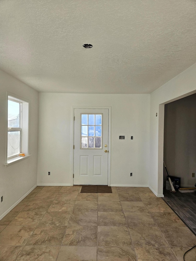 foyer entrance with a textured ceiling and baseboards