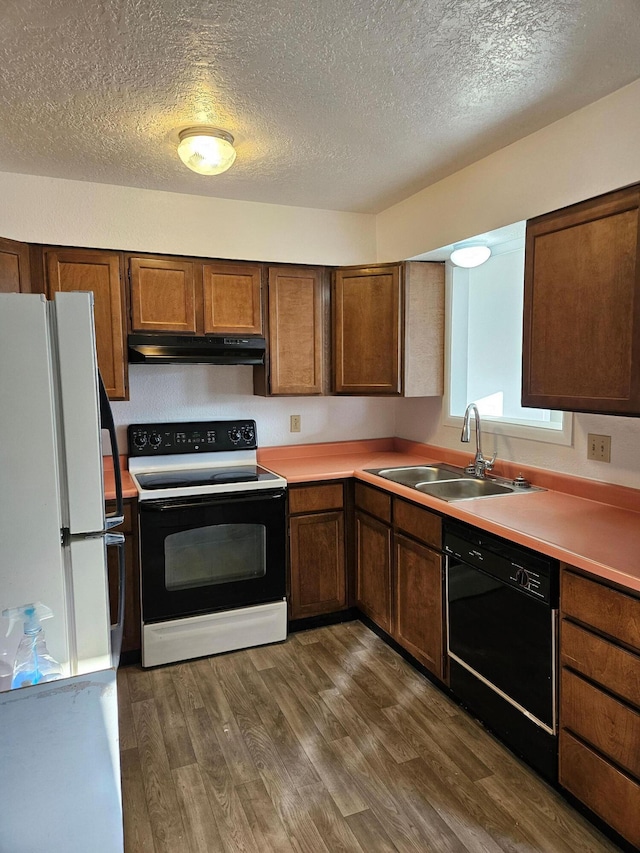 kitchen with electric range, dishwasher, freestanding refrigerator, under cabinet range hood, and a sink