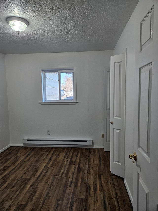 unfurnished room featuring a textured ceiling, baseboards, baseboard heating, and dark wood-type flooring