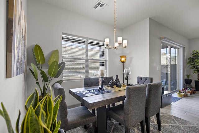 dining area featuring a chandelier, visible vents, and wood finished floors