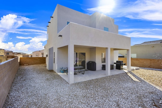 rear view of house featuring a fenced backyard, a patio, and stucco siding