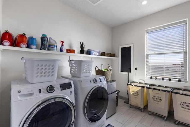 clothes washing area featuring a textured ceiling, laundry area, and washer and clothes dryer