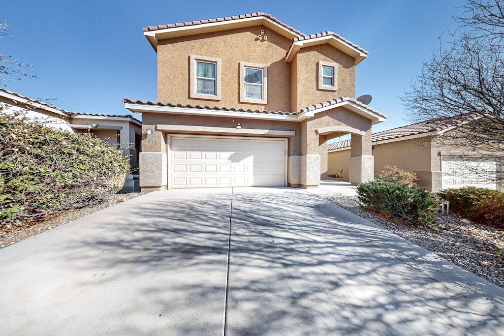 view of front of house featuring concrete driveway, an attached garage, a tiled roof, and stucco siding