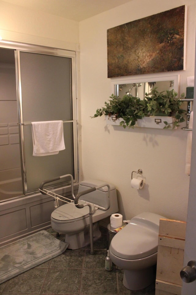 bathroom featuring toilet and combined bath / shower with glass door