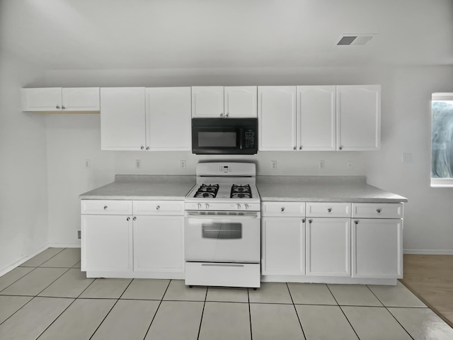 kitchen with white cabinets, white gas range, and light tile patterned floors