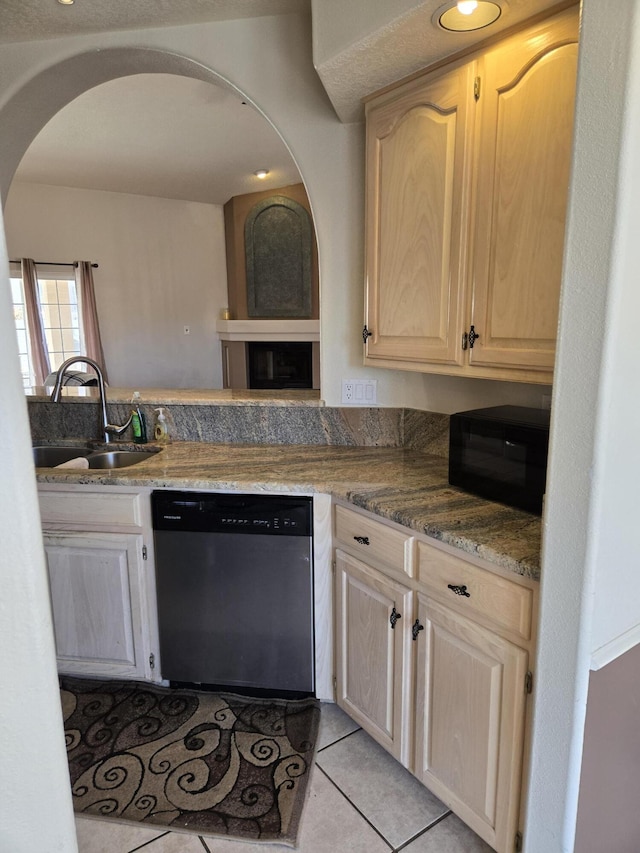 kitchen featuring light stone countertops, stainless steel dishwasher, light brown cabinets, sink, and light tile patterned floors