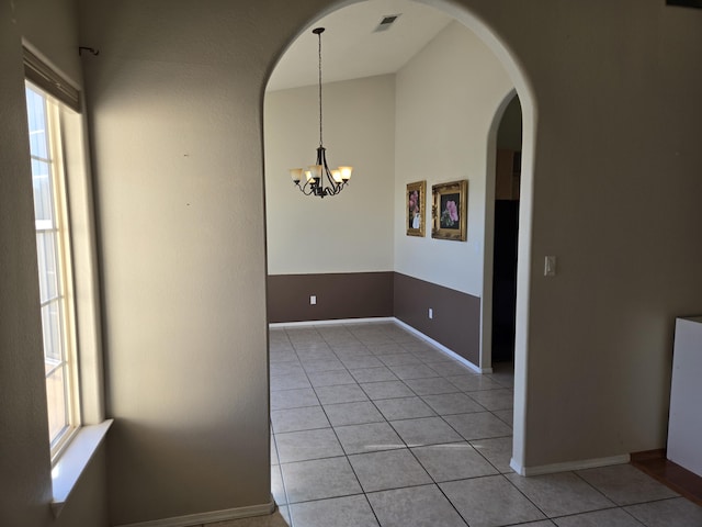 tiled empty room with a notable chandelier