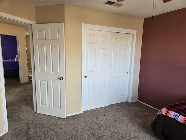 unfurnished bedroom with a textured ceiling, a closet, and dark carpet