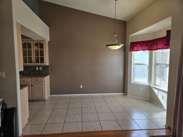 unfurnished dining area featuring light tile patterned floors and vaulted ceiling