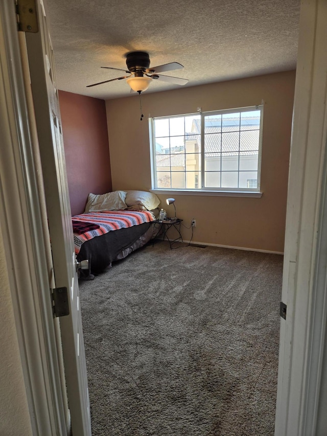 carpeted bedroom featuring ceiling fan and a textured ceiling