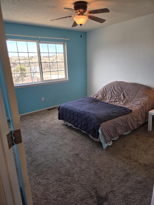 carpeted bedroom featuring ceiling fan and a textured ceiling