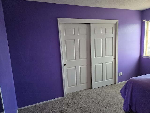 bedroom with light carpet, a textured ceiling, and a closet